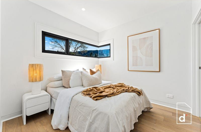 Bedroom with a bed, nightstand, artwork, and corner window with a view.