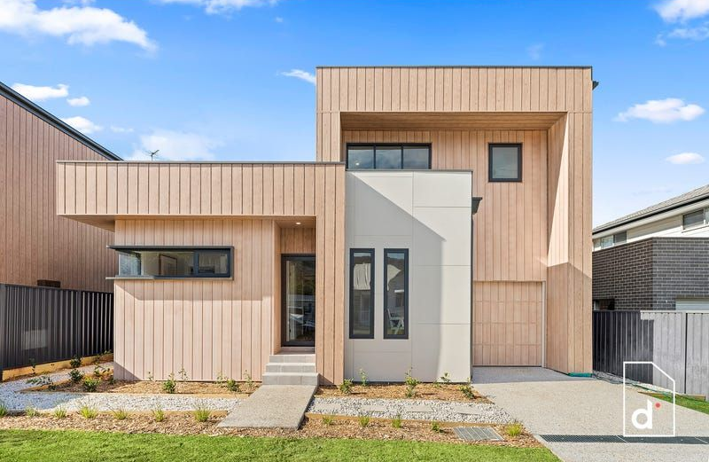 Modern two-story house with light wood siding, a concrete walkway, and a small front yard.