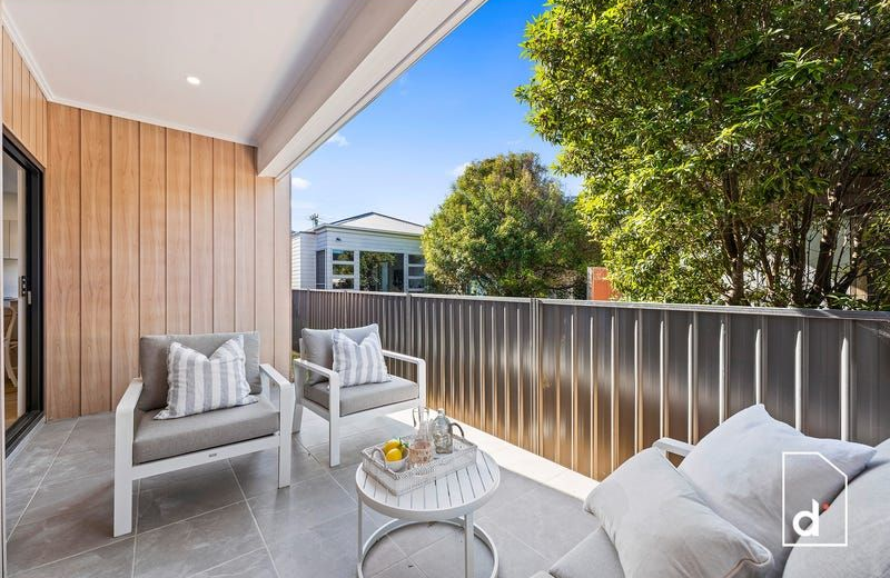 Balcony with gray furniture, wooden walls, and blue sky.