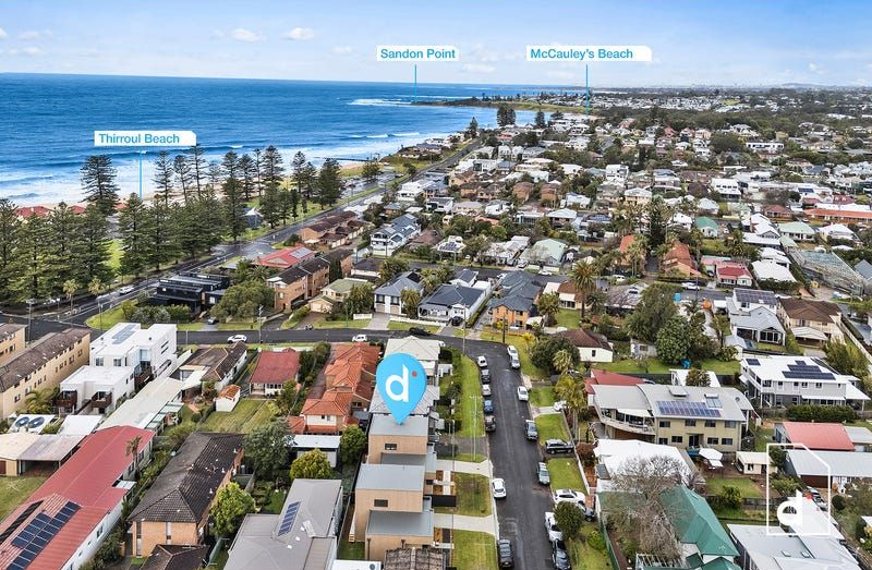 Aerial view of a coastal town, with beaches, houses, and the ocean visible.