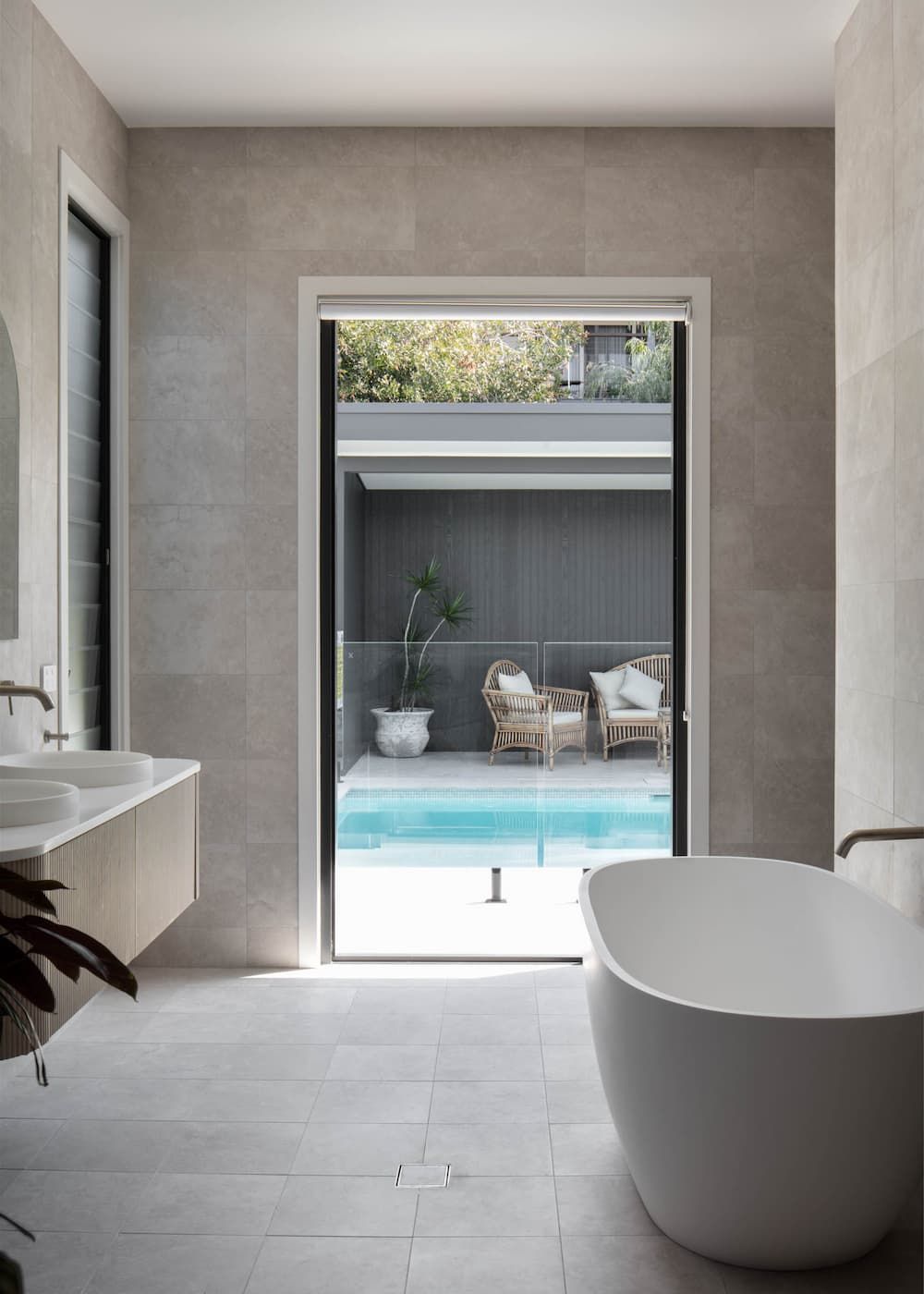 Bathroom with tub facing open doorway to a pool and outdoor seating area.