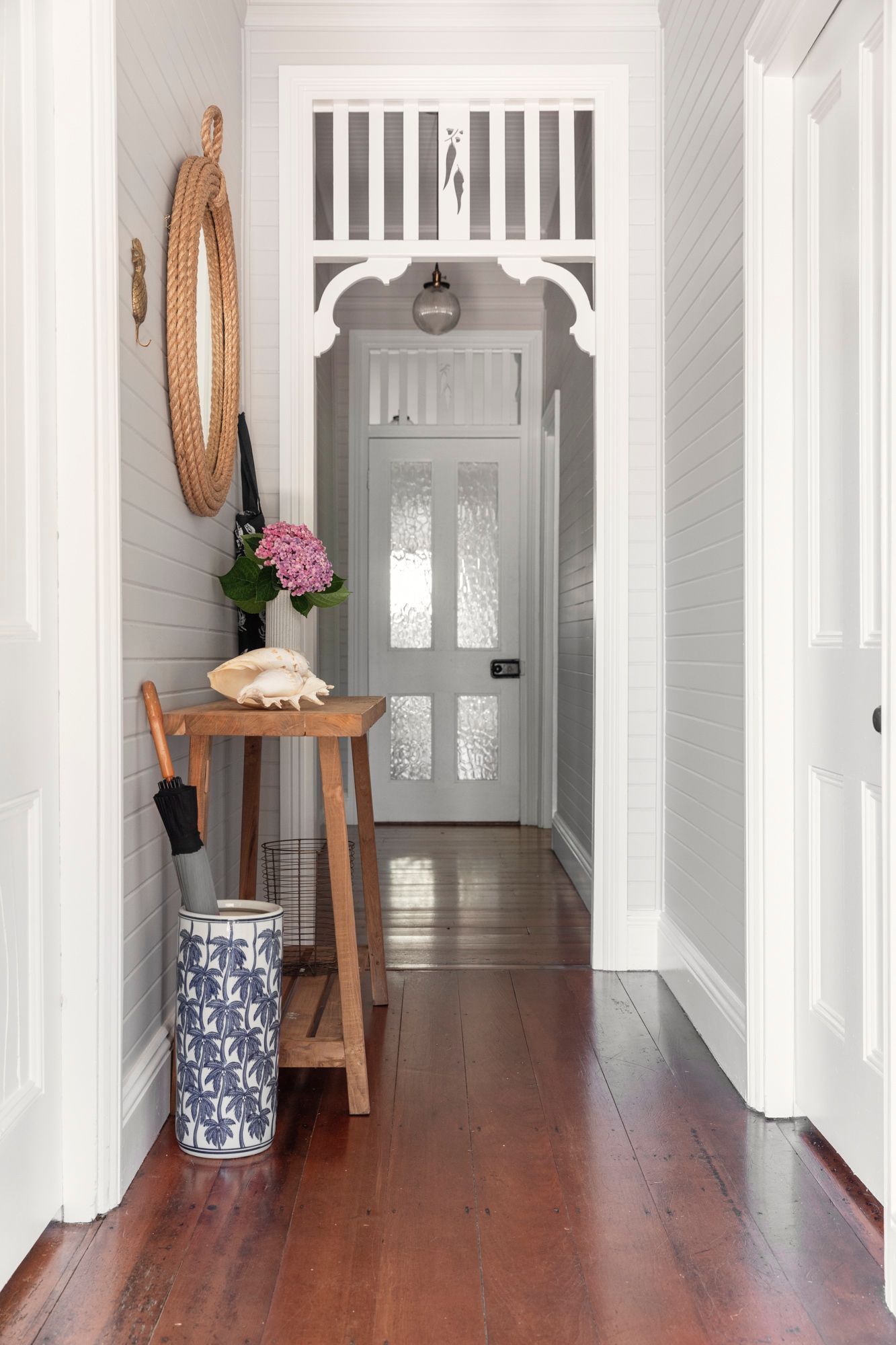 Hallway with wood floors, white trim, and an entryway table with decor.