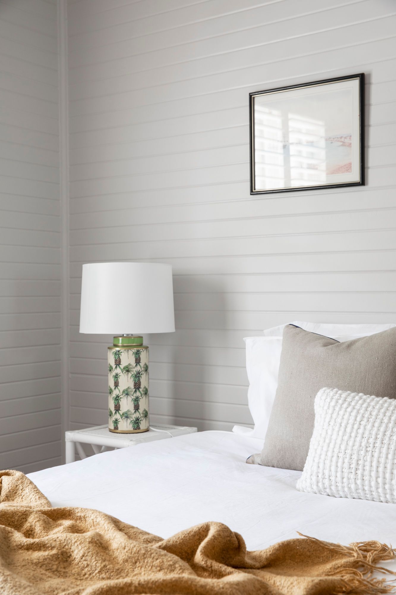 Bedroom with a white bed, decorative pillows, and a lamp on a nightstand.