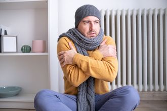 man in scarf and hat freezing in a home with a heating problem