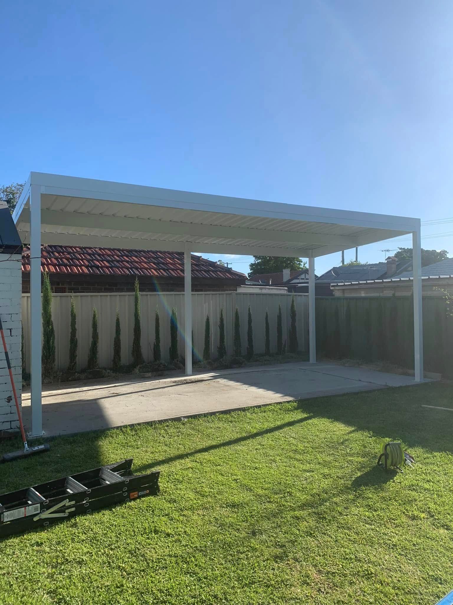 A white carport is sitting on top of a lush green lawn in a backyard.