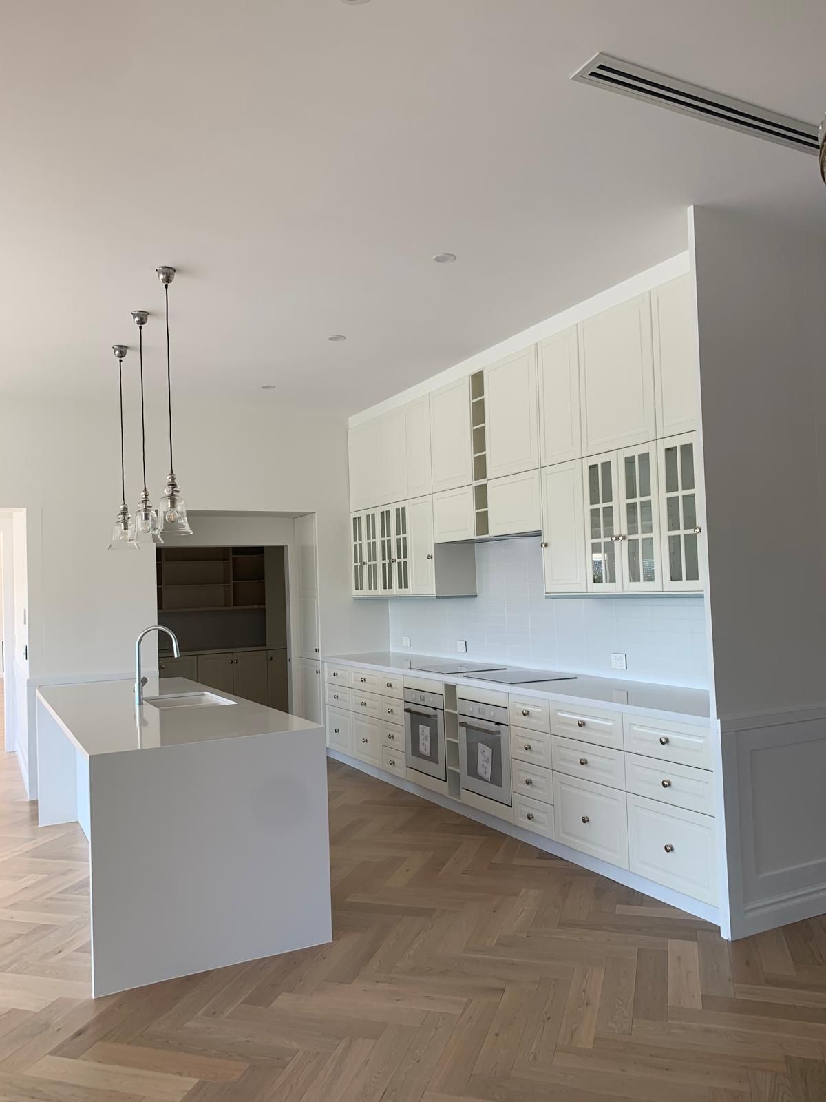 A kitchen with white cabinets and a wooden floor.