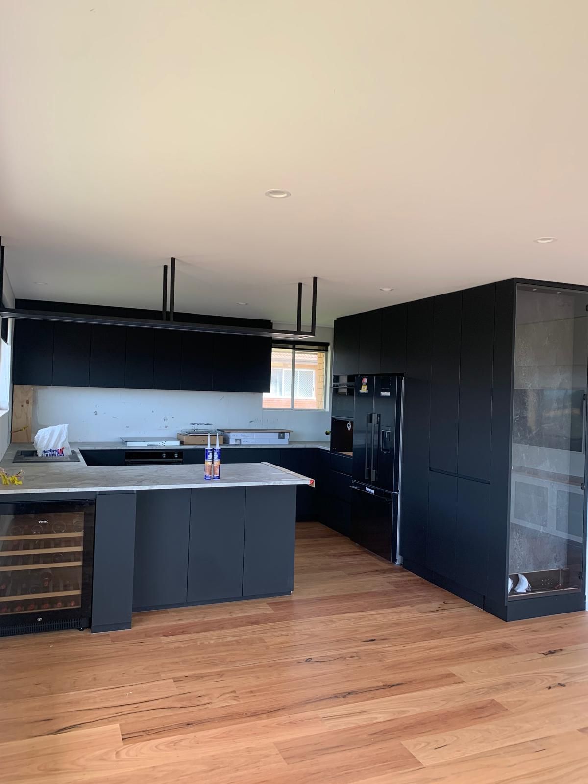 A kitchen with black cabinets and a wooden floor.