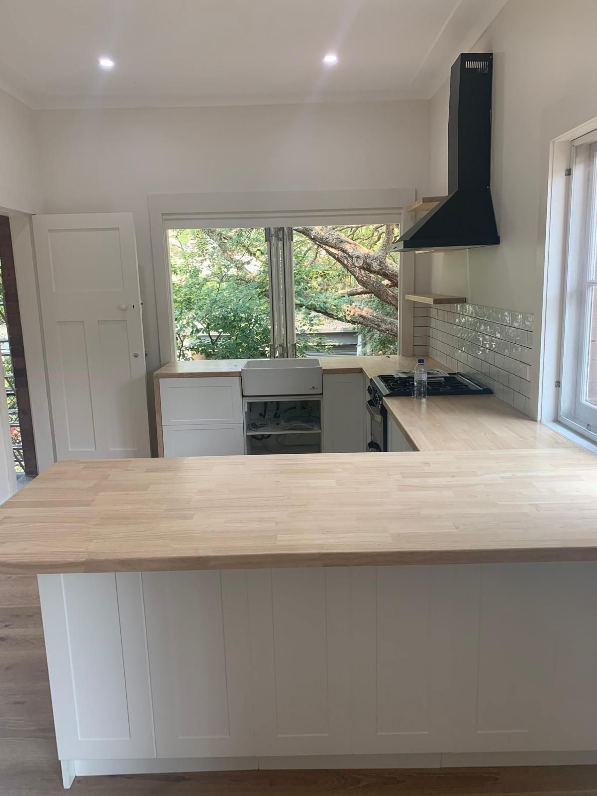 A kitchen with white cabinets and a wooden counter top.