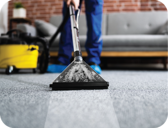 A person is cleaning a carpet with a vacuum cleaner.