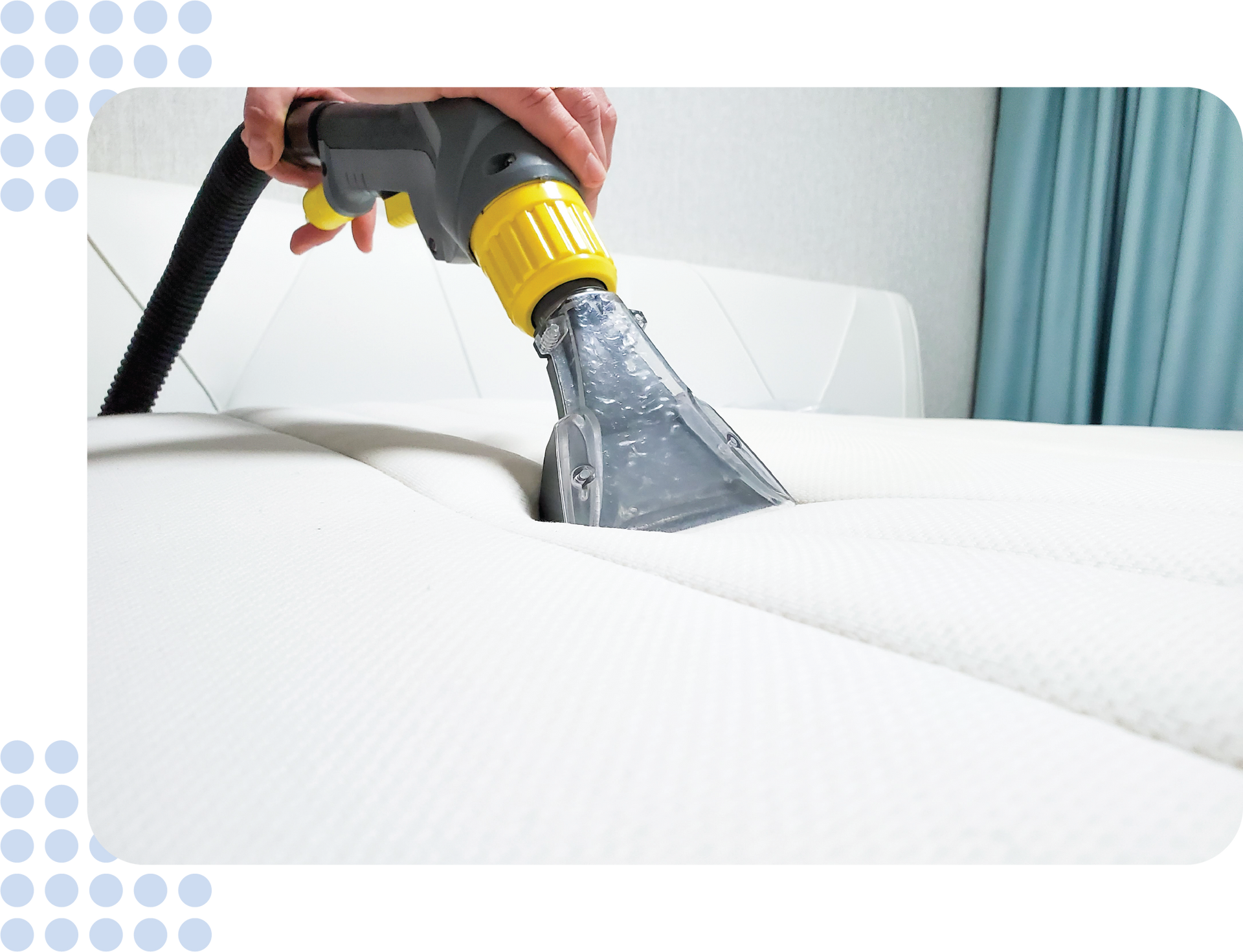 A person is cleaning a white couch with a vacuum cleaner.