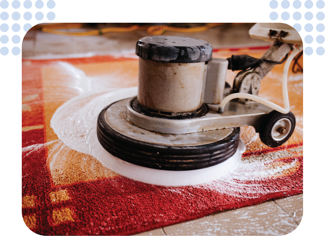 A machine is cleaning a red rug on the floor.