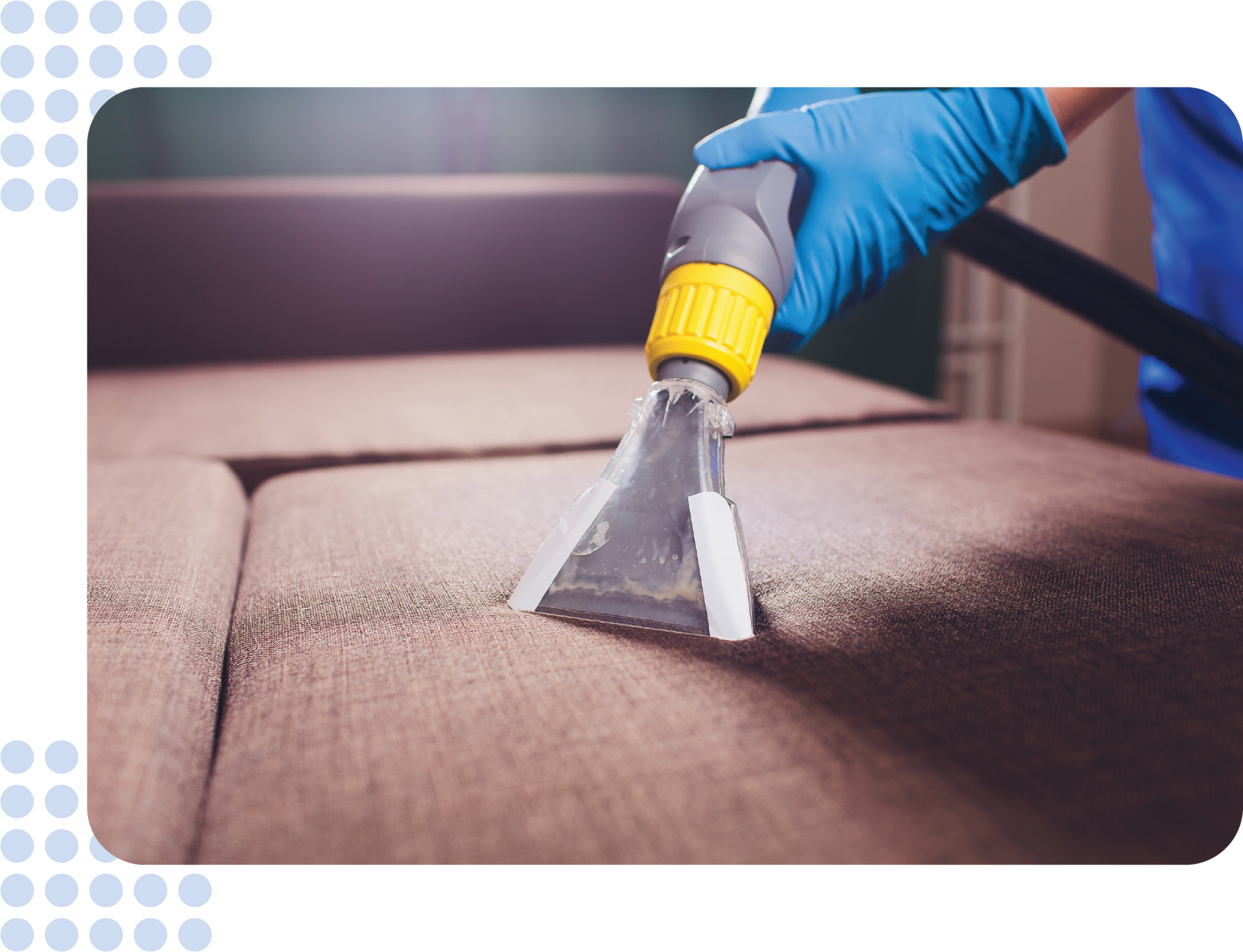 A person is cleaning a couch with a vacuum cleaner.