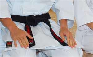 a person wearing a karate uniform with a black belt .