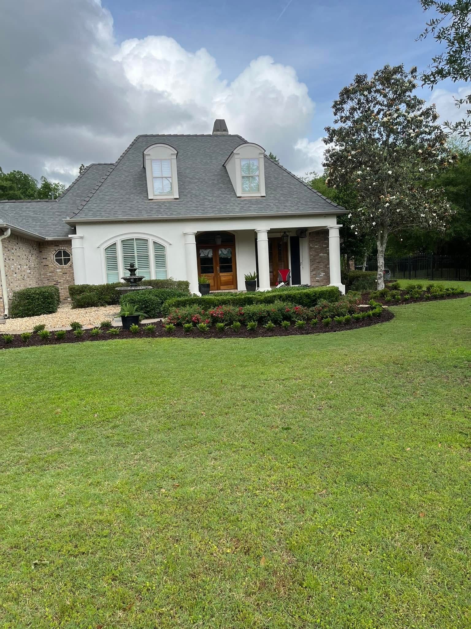A white house with a gray roof and a large lawn in front of it.