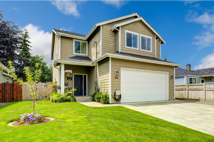 A large house with a white garage door and a lush green lawn.