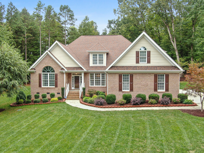 A large brick house with a large lawn in front of it