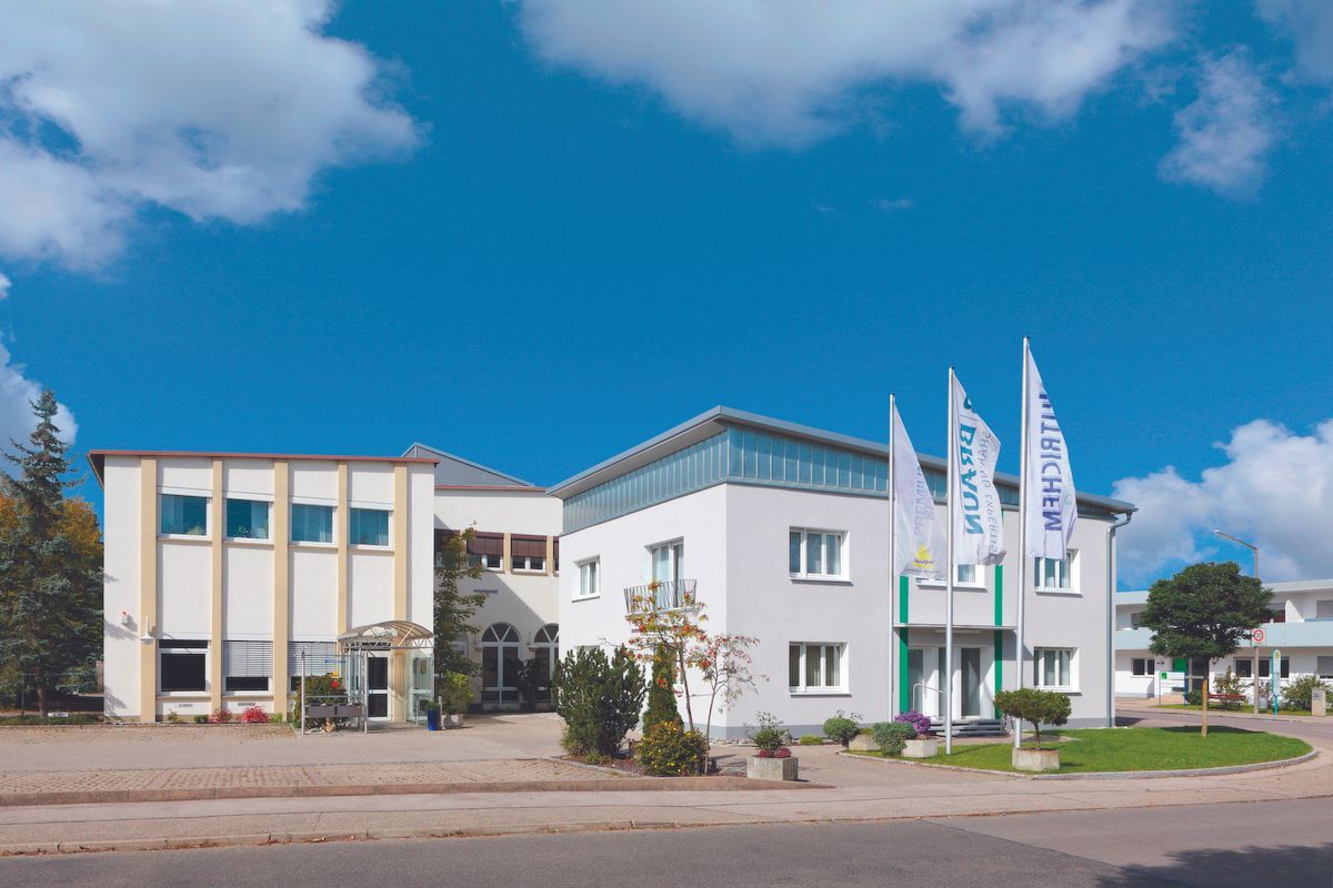 Edificio con più sezioni, bandiere blu e cielo limpido.