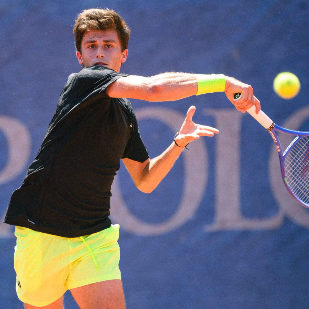 Tennista in azione, mentre colpisce una palla gialla con una racchetta. 