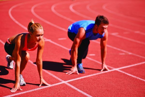 Due atleti, una donna e un uomo, sulla linea di partenza di una pista rossa, accovacciati e pronti a correre.