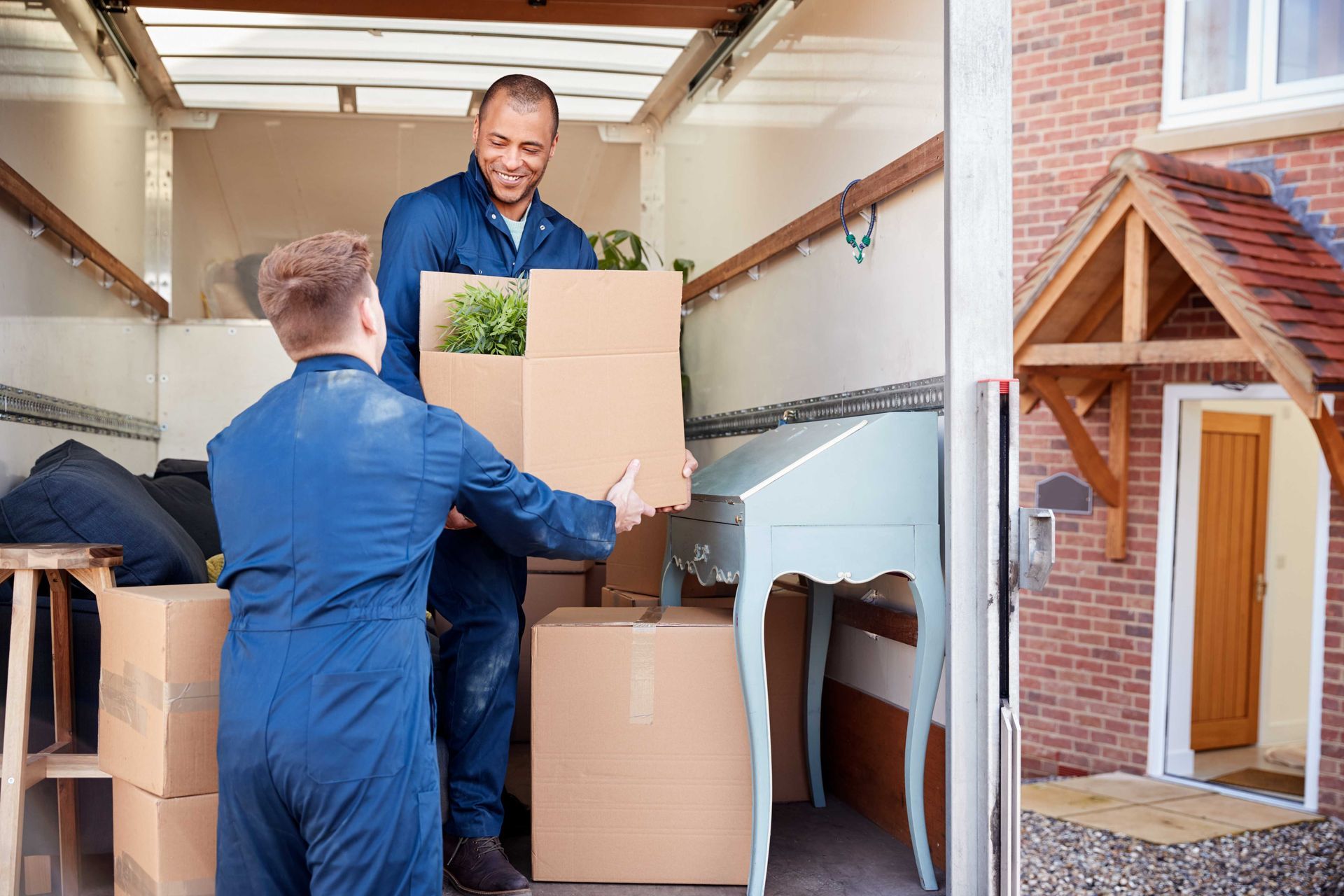 two men are loading boxes into a moving truck .