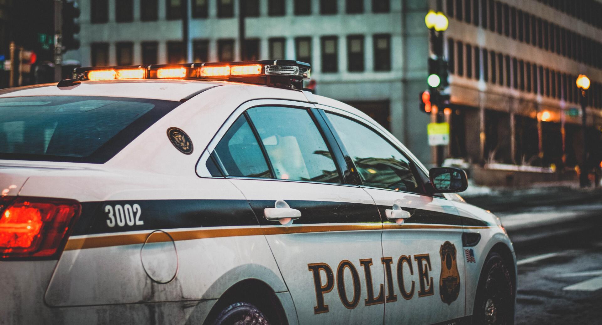 A police car is parked on the side of the road in front of a building.
