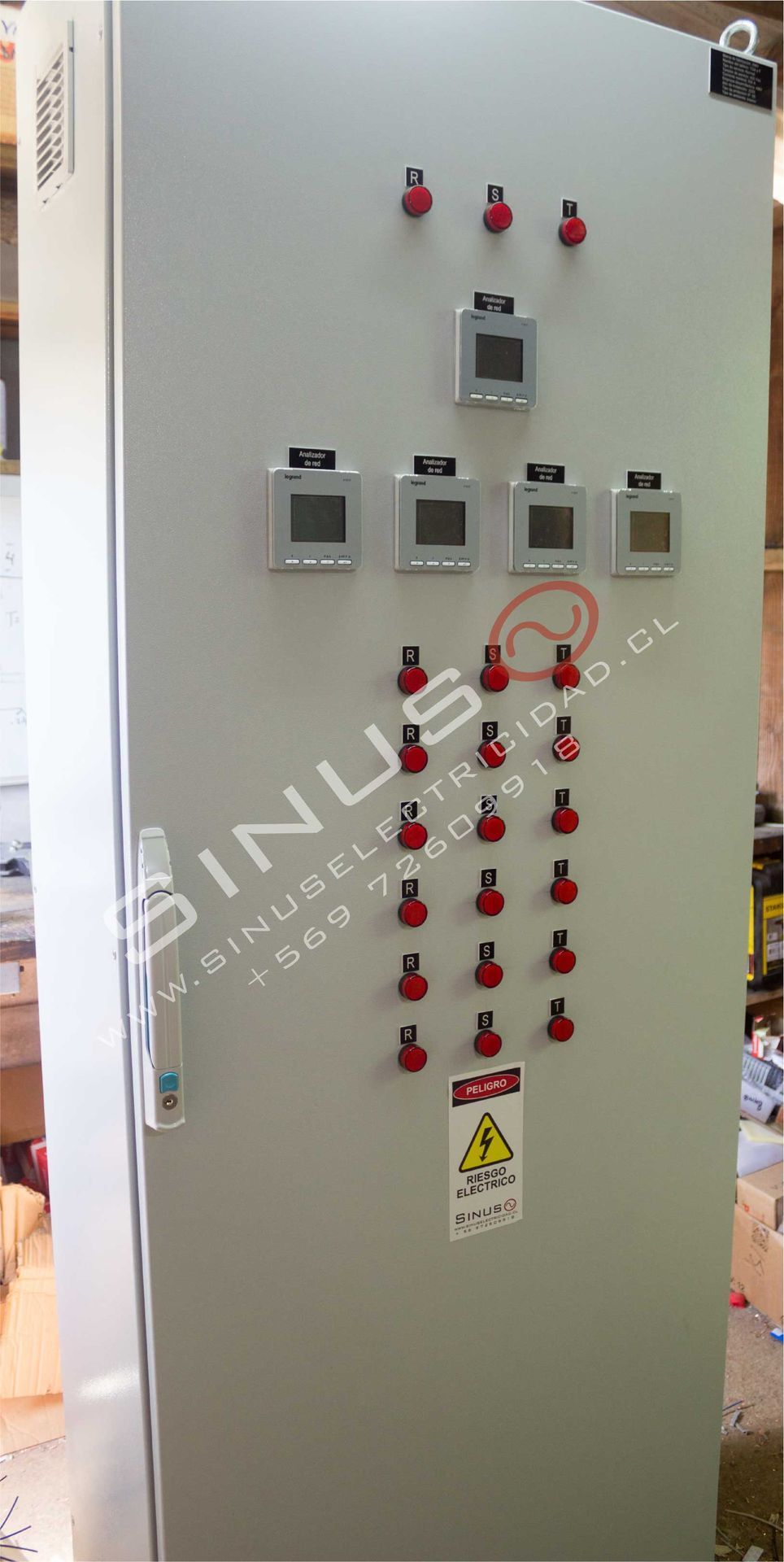 Armario alto de control eléctrico con interruptores, medidores y etiquetas de advertencia rojas en el panel frontal.