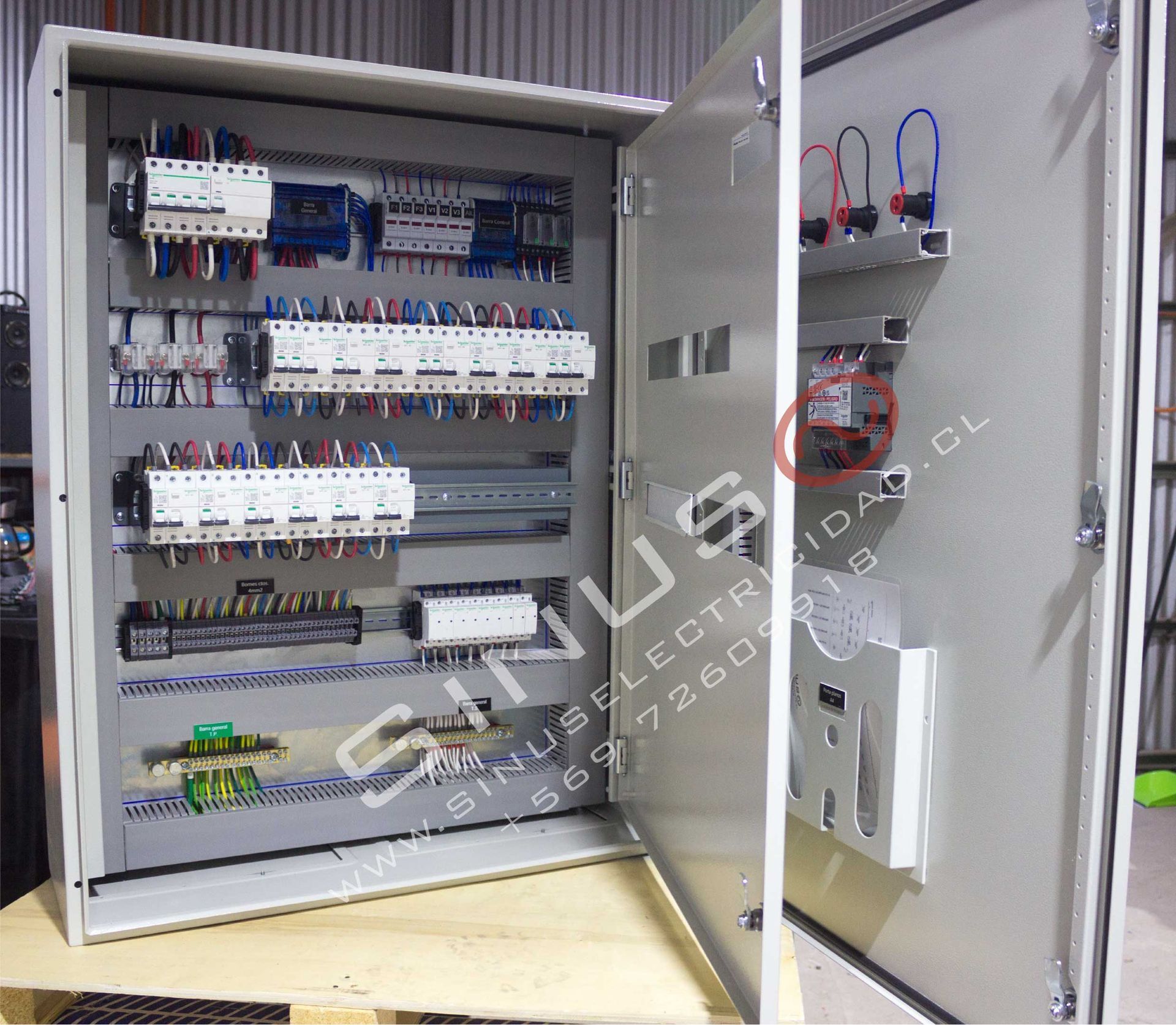 Armario de control eléctrico abierto con disyuntores, cableado y componentes montados en la puerta interior.