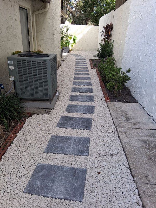 Stone path with stepping stones, gravel, and landscaping between two walls.