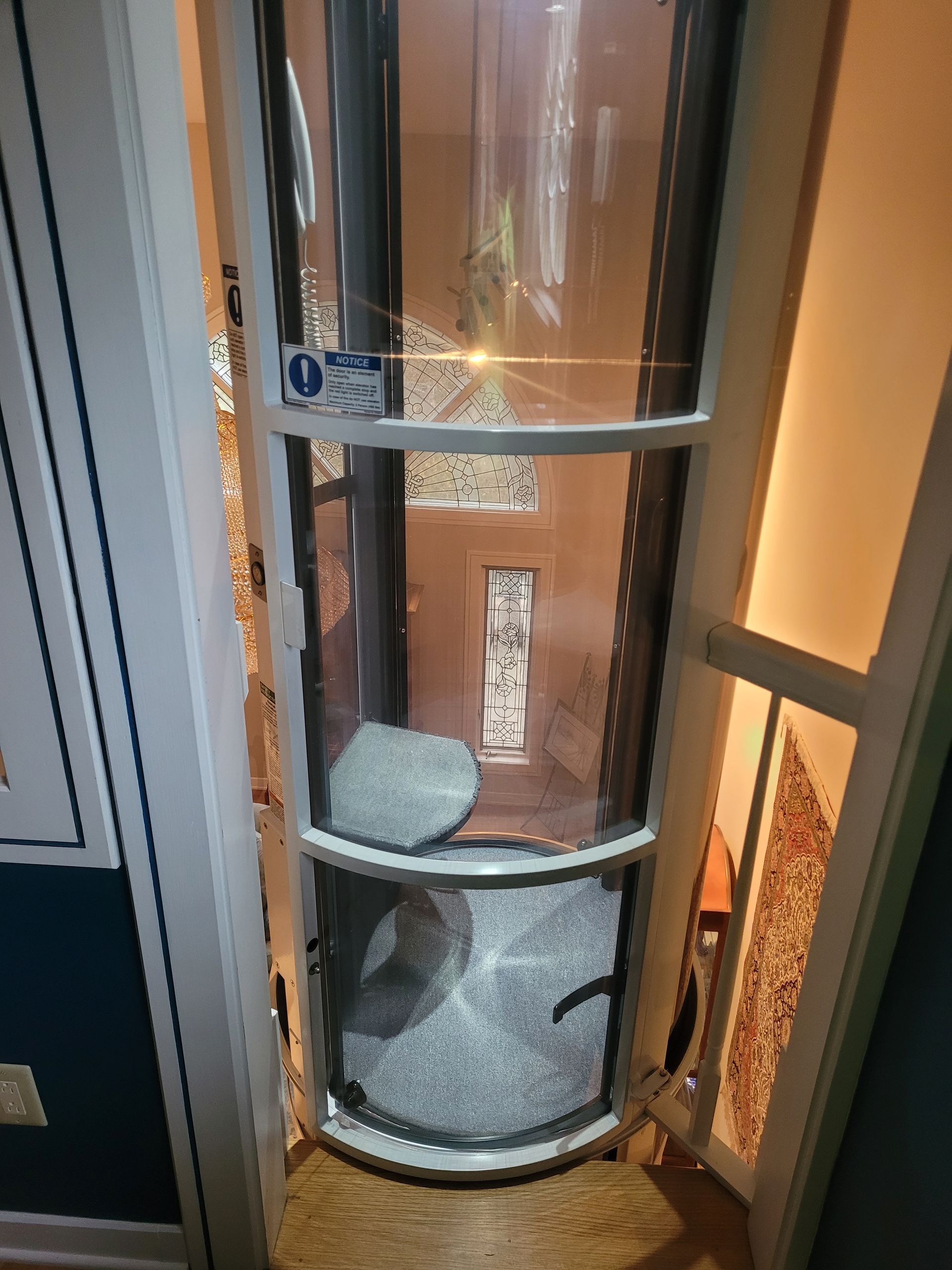 A glass elevator is sitting in a hallway next to a door.