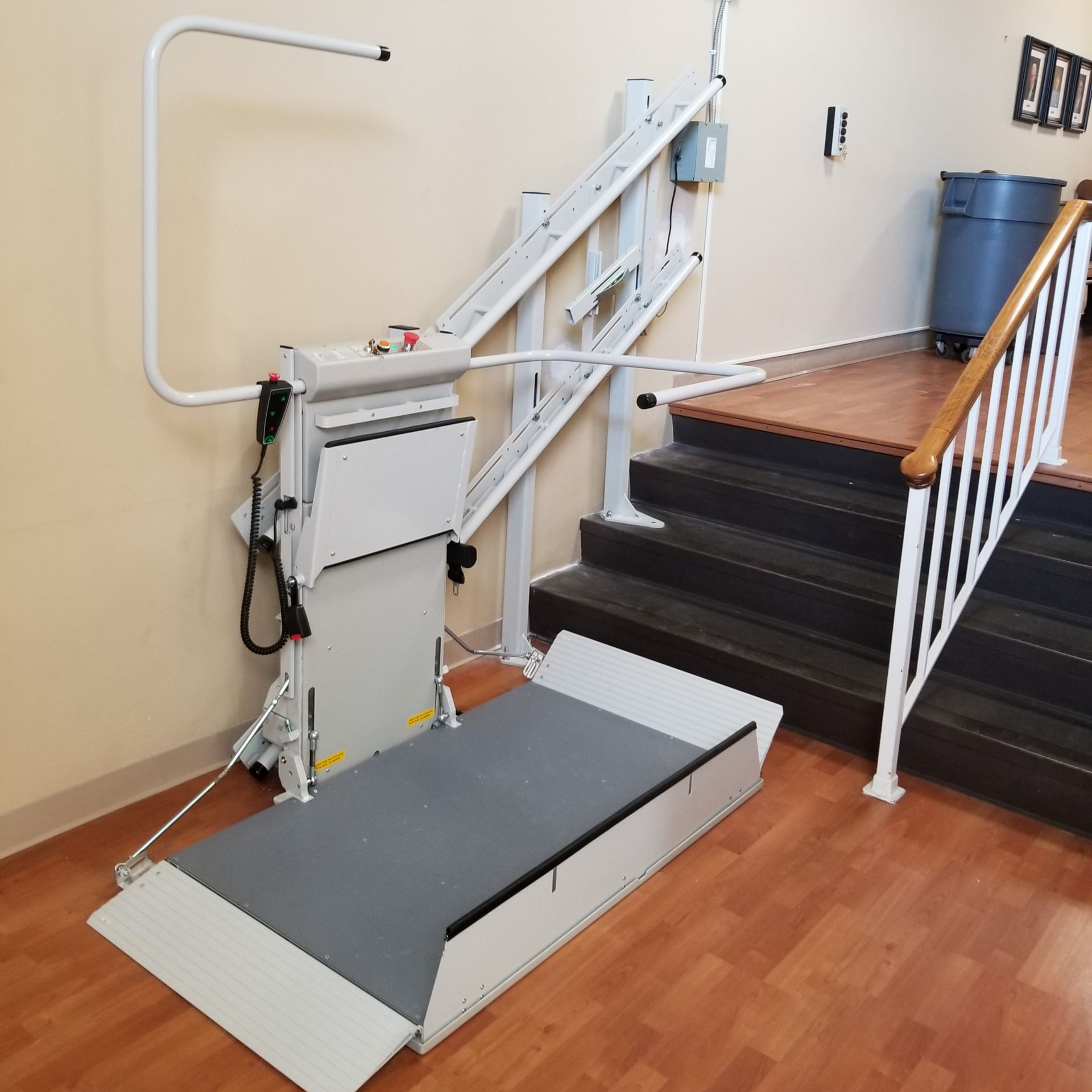 A stair lift with a gray seat and a wooden railing