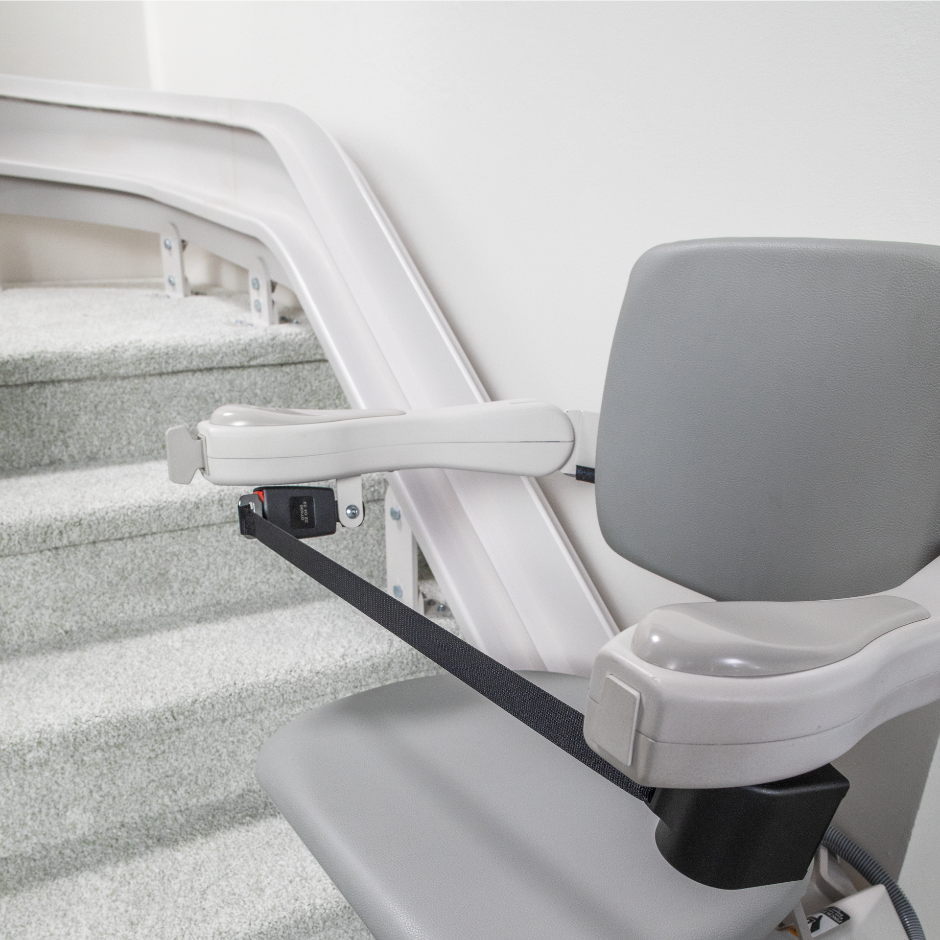 A stair lift with a gray seat and a white railing