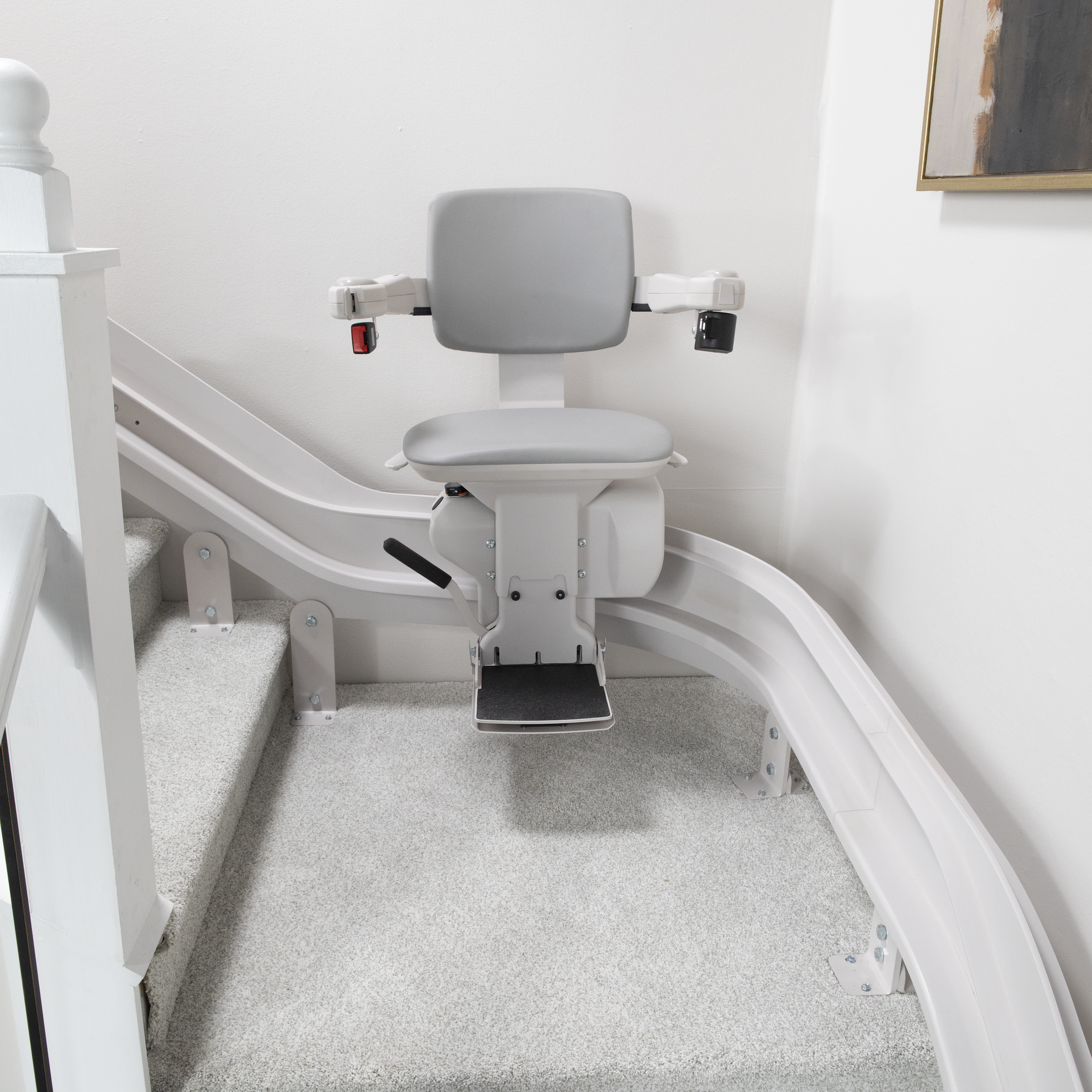 A stair lift with a gray seat and a wooden railing
