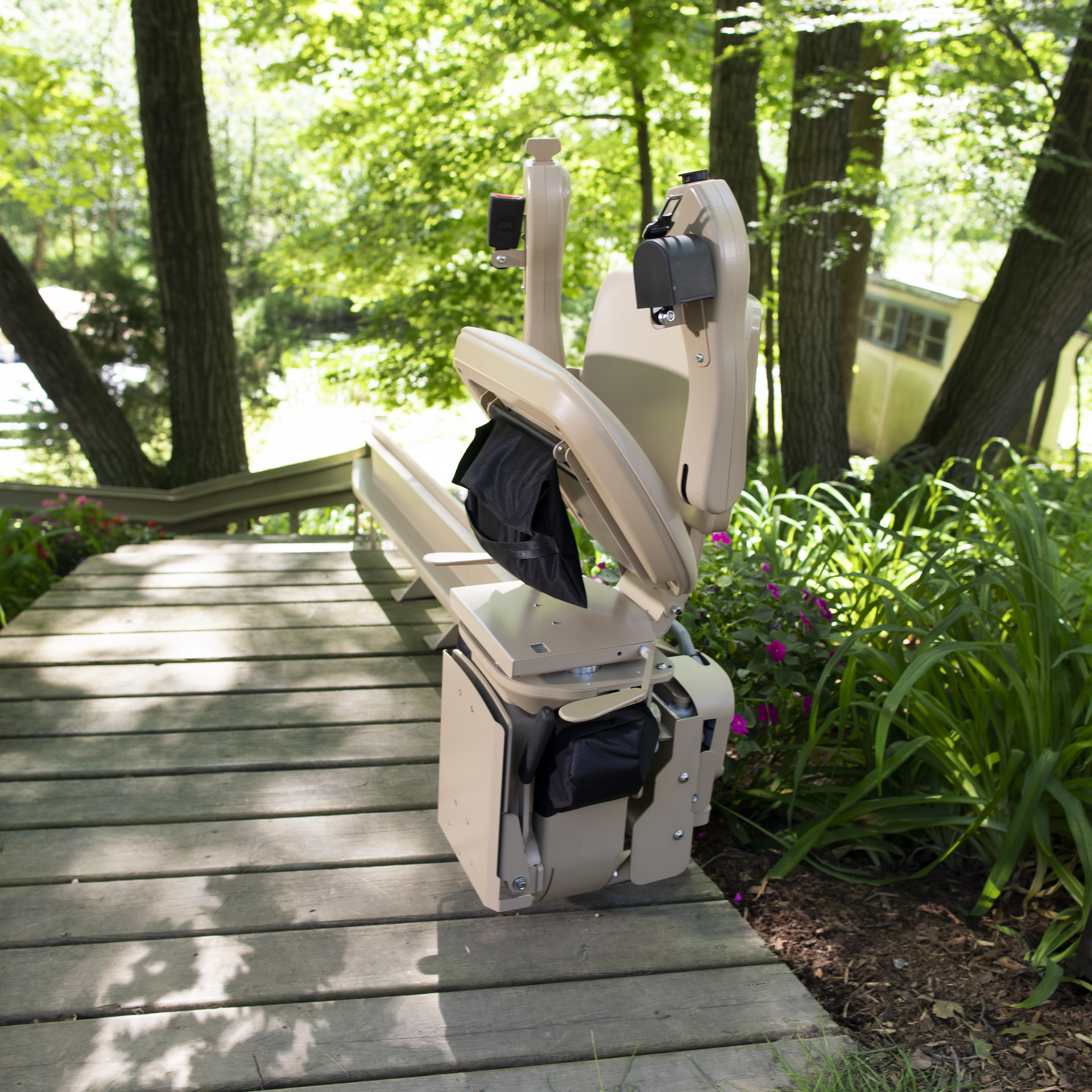 A stair lift sits on a wooden deck in the woods