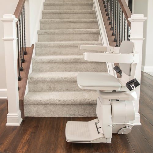 A stair lift is sitting on the bottom of a set of stairs.