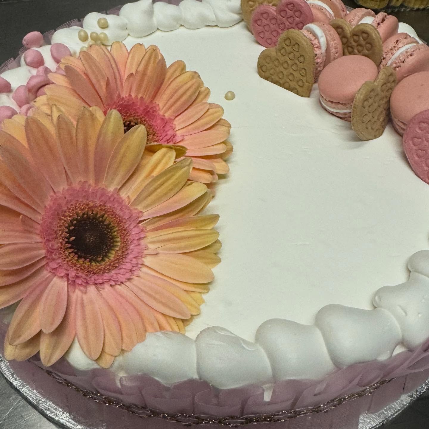 Torta decorata con fiori rosa, macaron e biscotti.