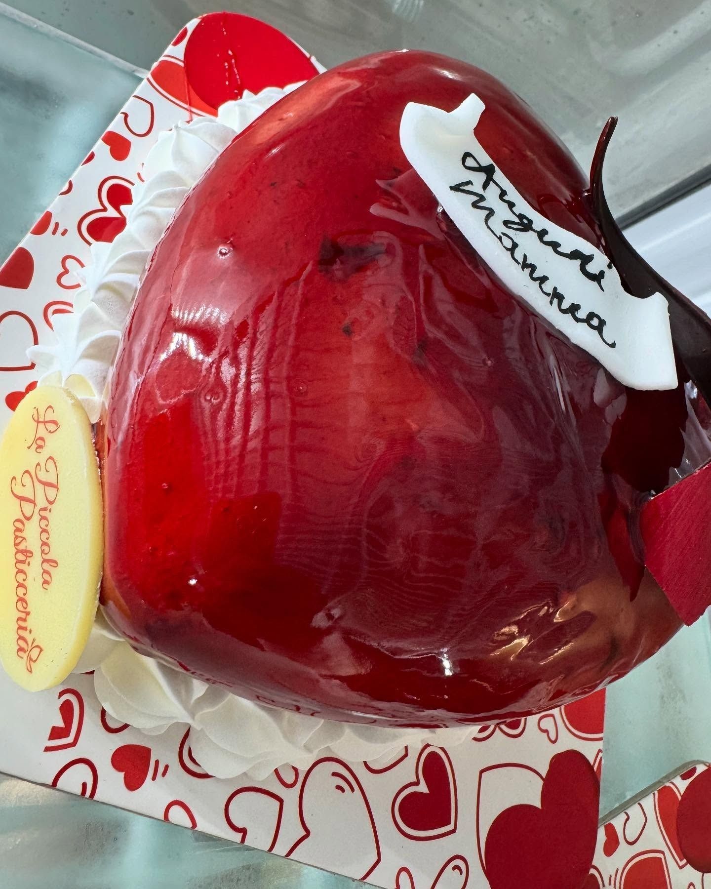 Torta a forma di cuore rosso glassata su un vassoio decorato con cuori. Glassa bianca e decorazione