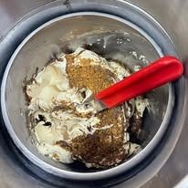 Gelato preparato con una spatola rossa all'interno di una gelatiera in acciaio inox.