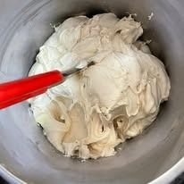 Glassa bianca in un secchiello, spatola rossa.