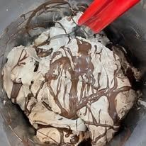 Gelato con salsa al cioccolato in una ciotola di metallo, cucchiaio rosso.