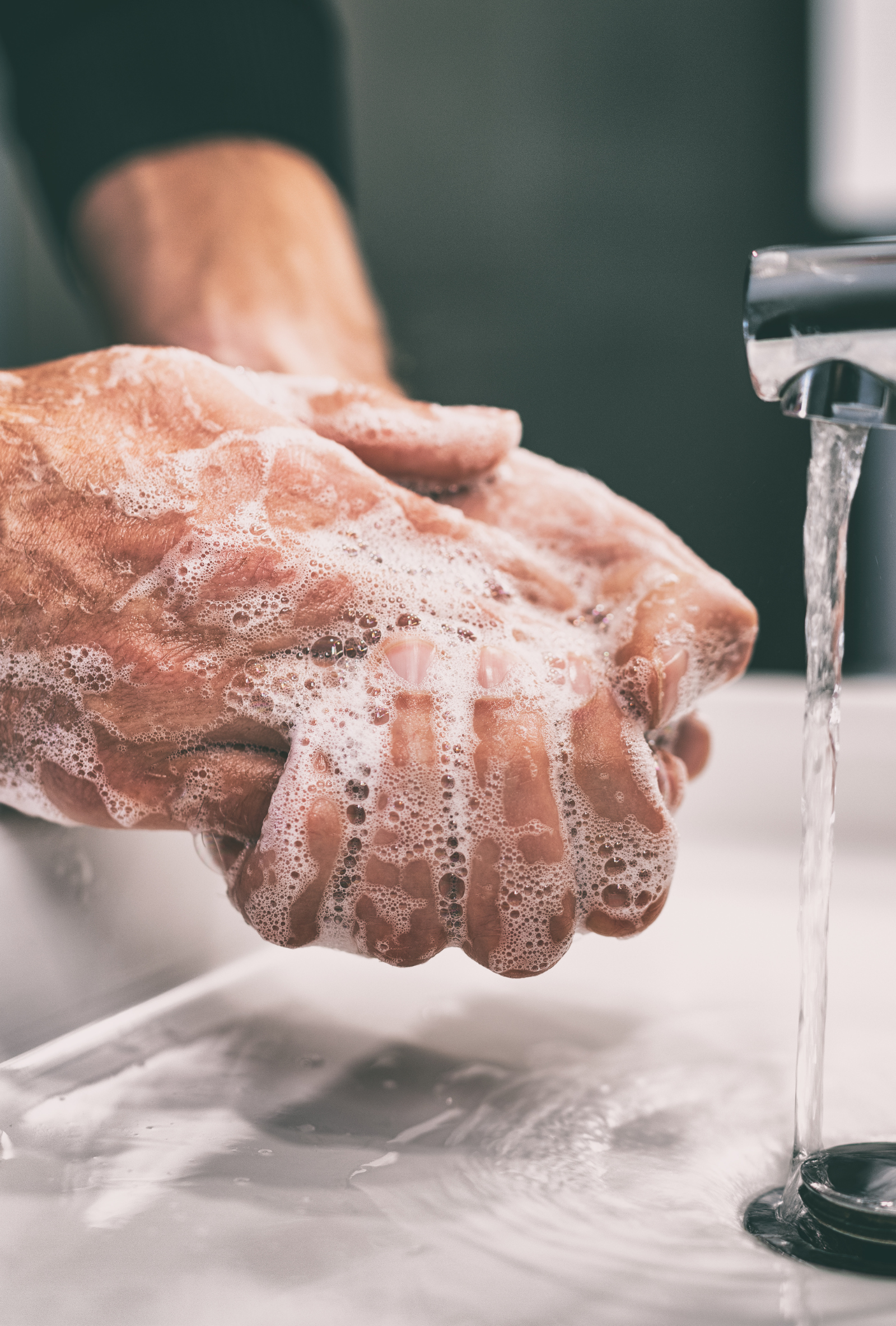 A person is washing their hands in a sink with soap and water.