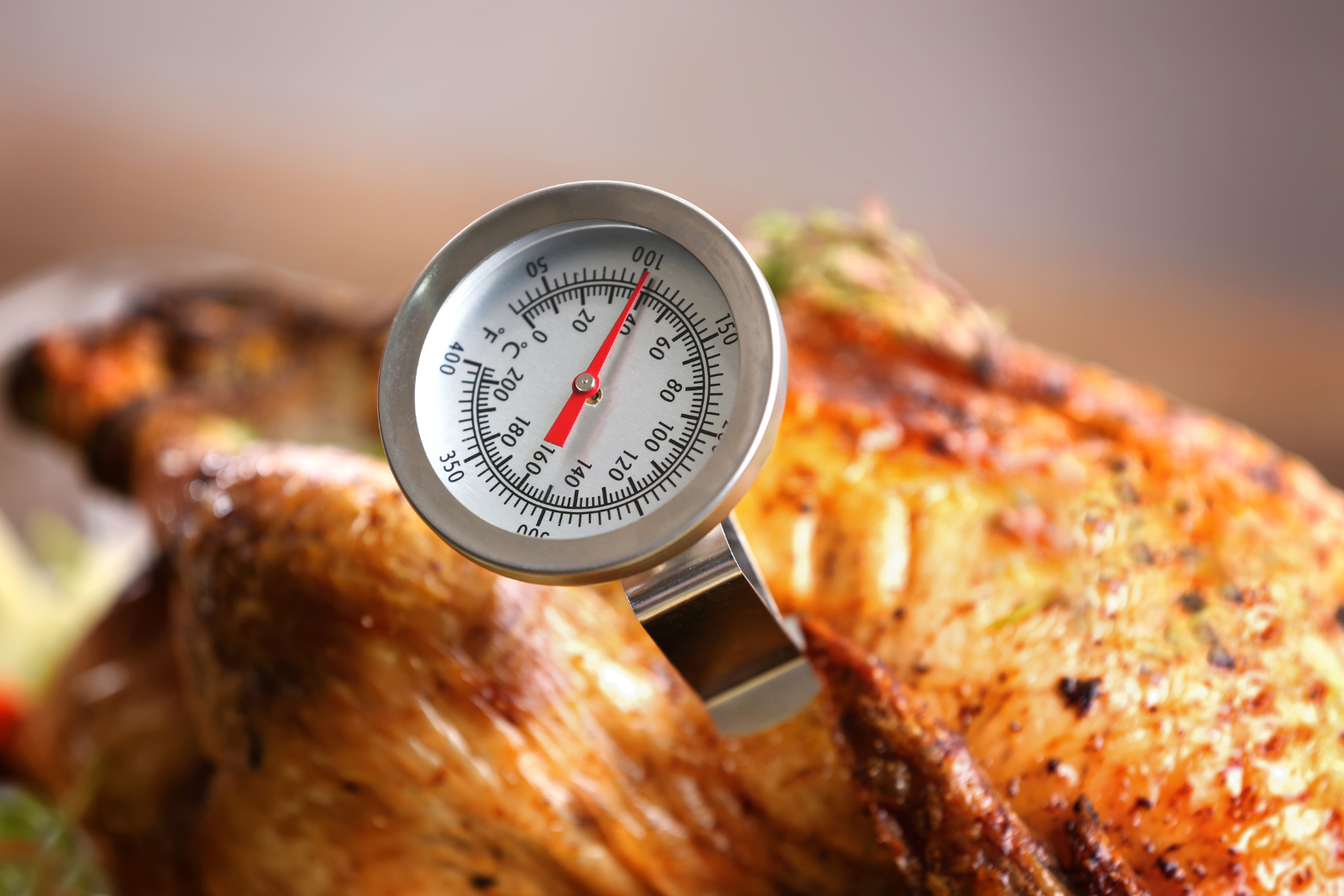 A thermometer is sitting on top of a roasted chicken.