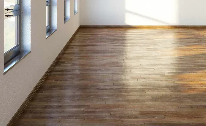 Empty room with hardwood floors, several windows along one wall, and bright sunlight.