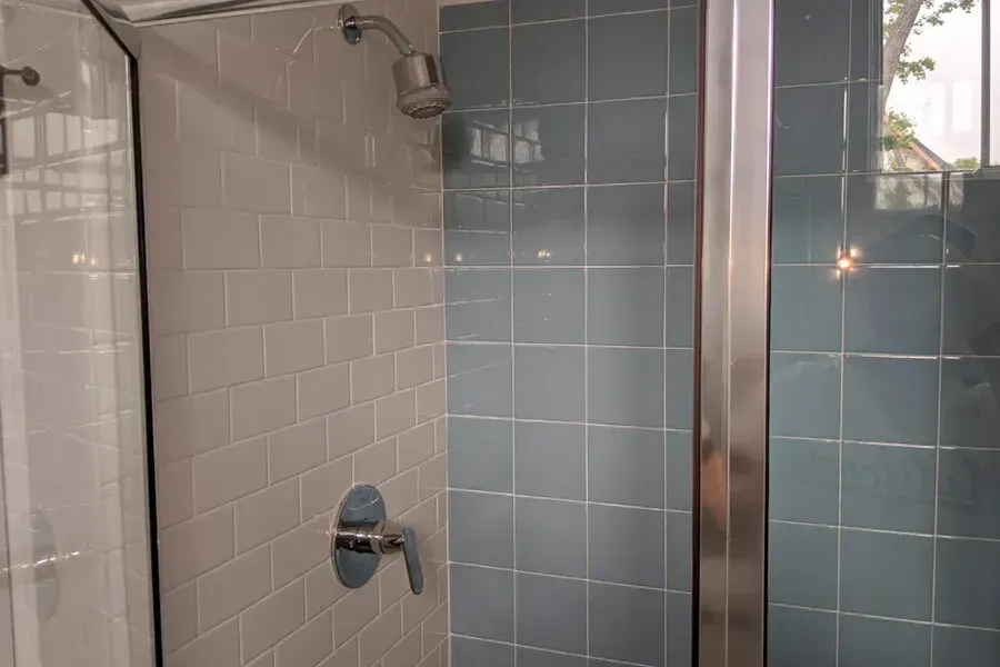 Shower with blue and white tiled walls, glass door, and chrome fixtures.