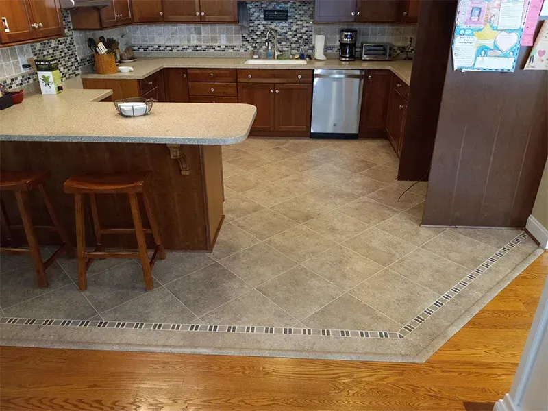 A kitchen with brown cabinets, granite countertops, and a tile floor, including a breakfast bar with stools.
