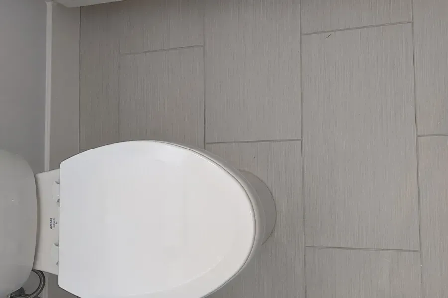 White toilet in a bathroom with light gray tiled walls.