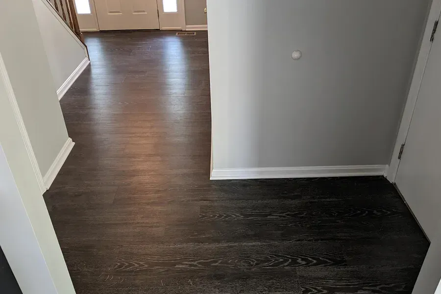 Dark wood floor in a hallway with gray walls and white trim