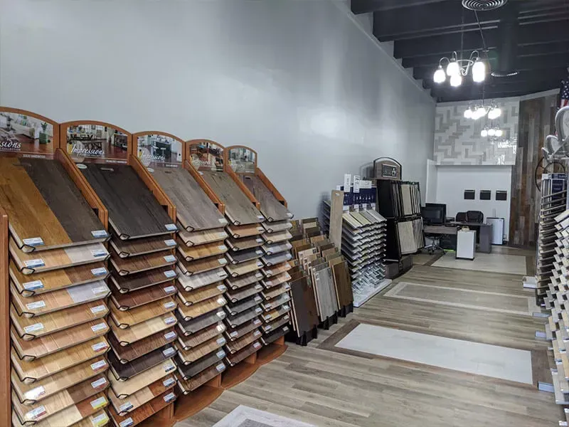 Interior of a flooring showroom displaying various wood and tile samples. The space has bright overhead lighting.