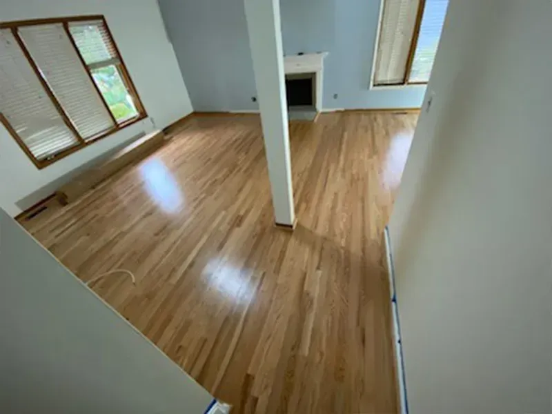 Light hardwood floors in a spacious room with light blue walls and a fireplace. A white pillar stands in the center.