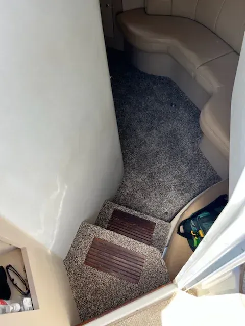 Staircase leading down into a boat cabin with carpeted steps and surrounding seating.