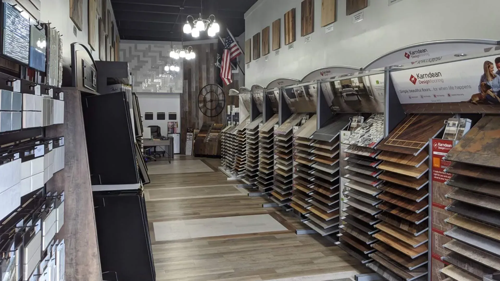 Interior of a flooring store. Displays of tile and wood samples line the walls. An American flag hangs in the center.